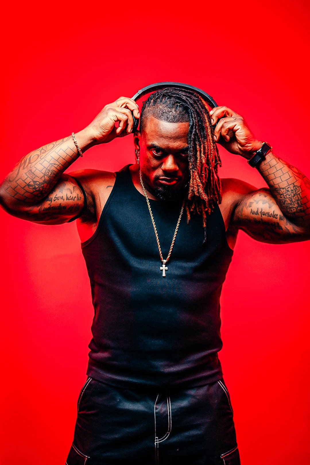 Dat Boi Jonni portrait on red background, headphones and gold cross